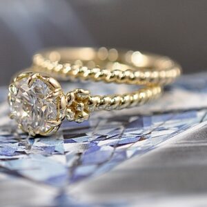 Gold-toned ring with a clear center stone and a textured split band.