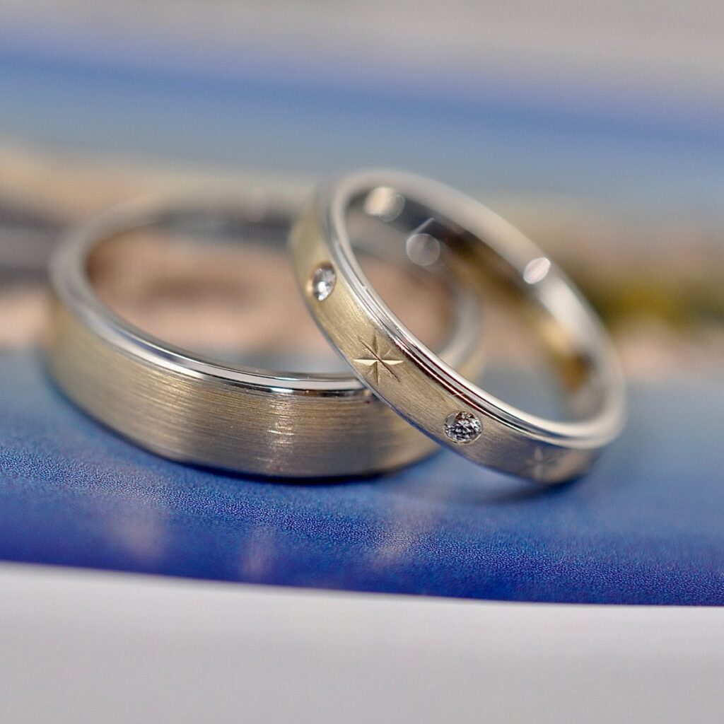 Pair of silver-toned wedding bands, one brushed and one with small inset stones.
